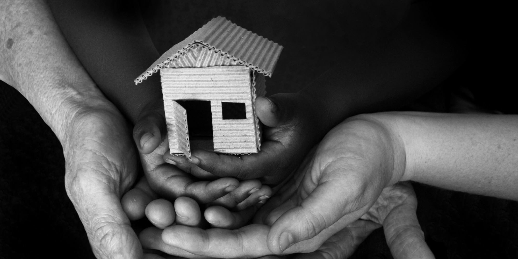 Image of multiple hands holding a home.